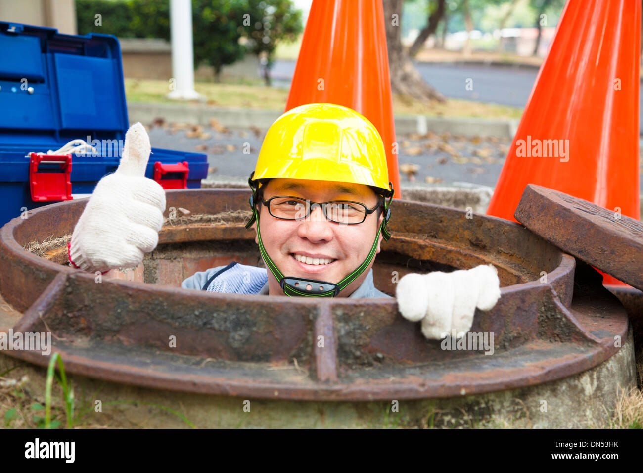 sewerage worker in the manhole with thumb up Stock Photo
