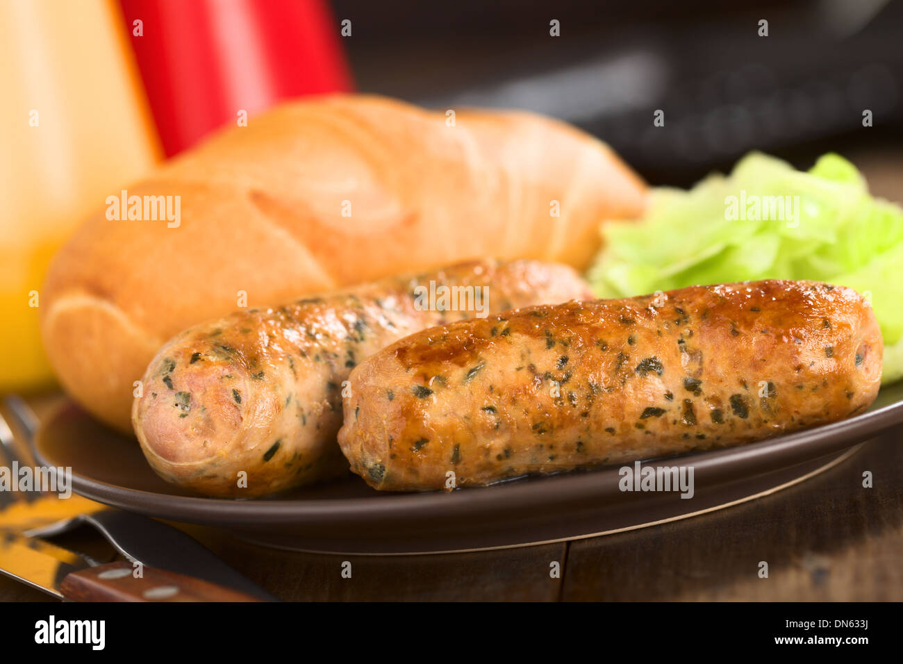 Fried bratwurst with bun, traditional German fast food served on plate with green salad Stock Photo