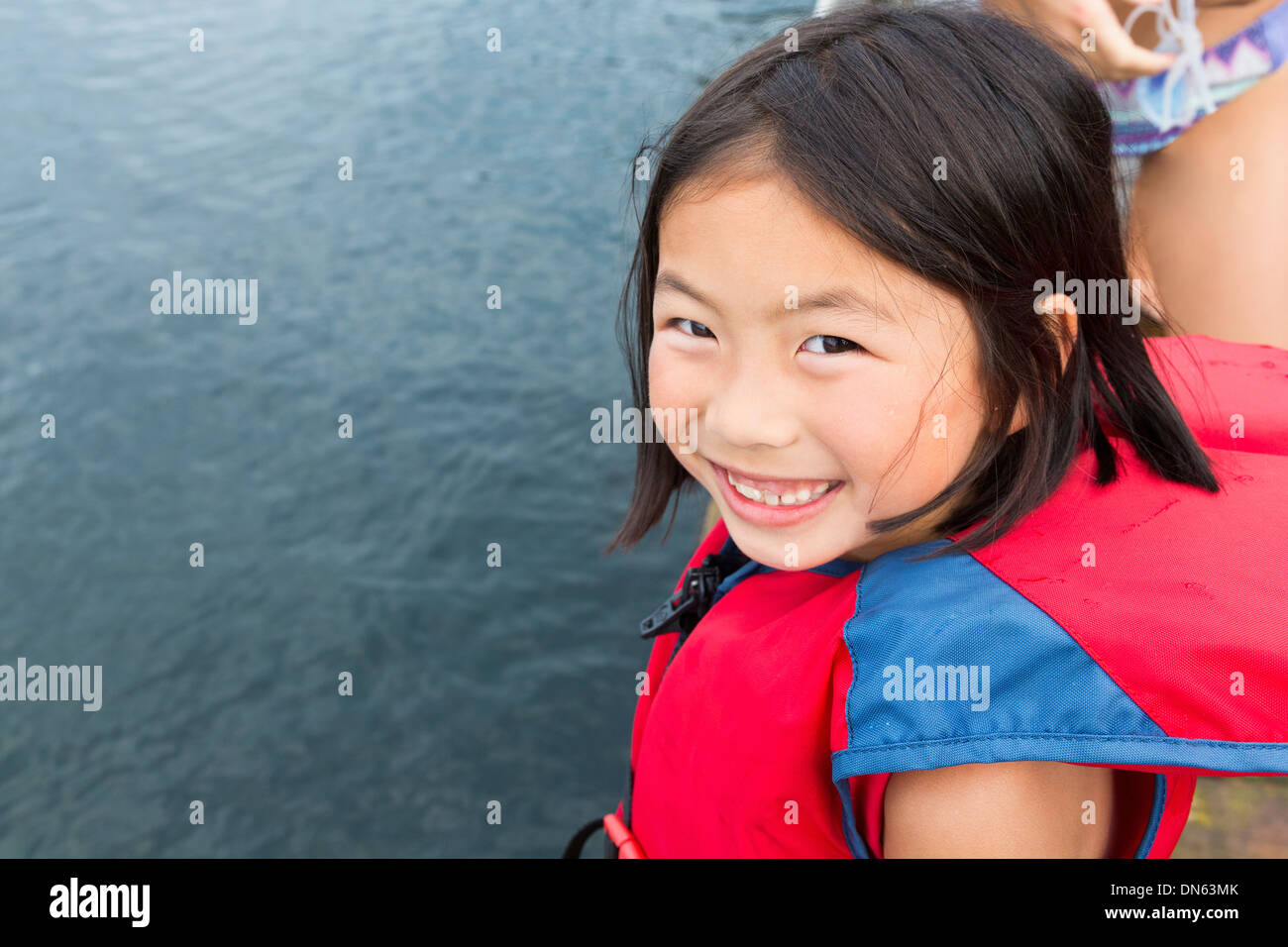 Mixed race girl smiling by lake Stock Photo