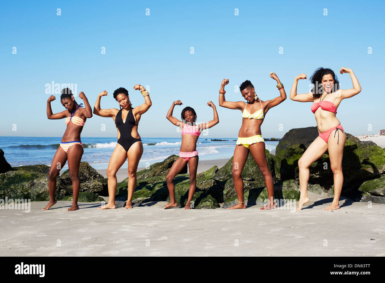 Women flexing muscles on beach Stock Photo