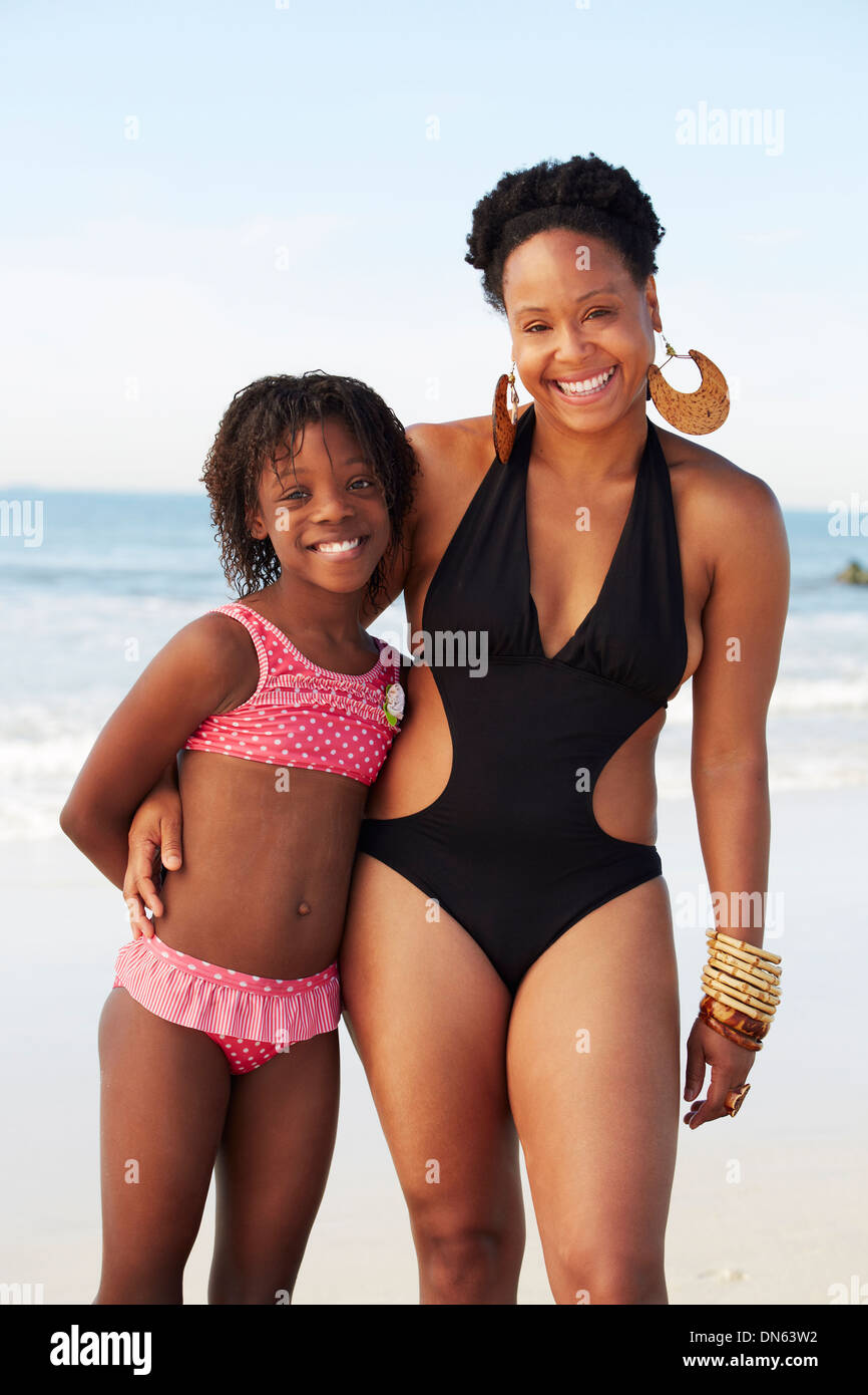 Black mother and daughter smiling on beach Stock Photo