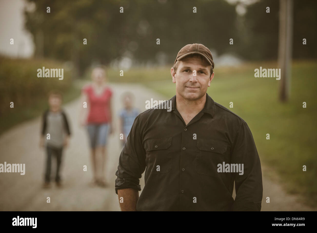 Caucasian farmer with family on dirt road Stock Photo