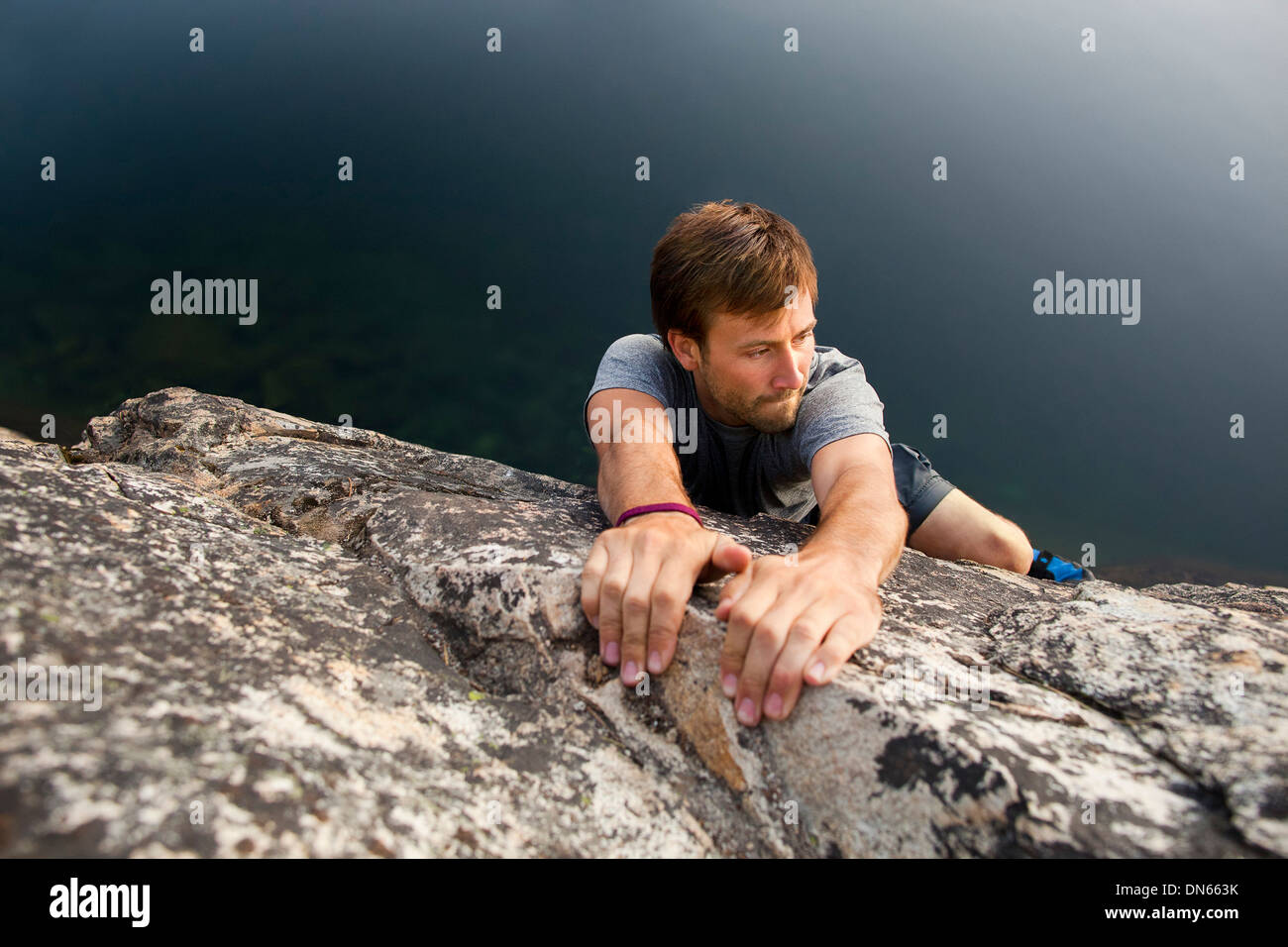 Climber scaling steep rock face Stock