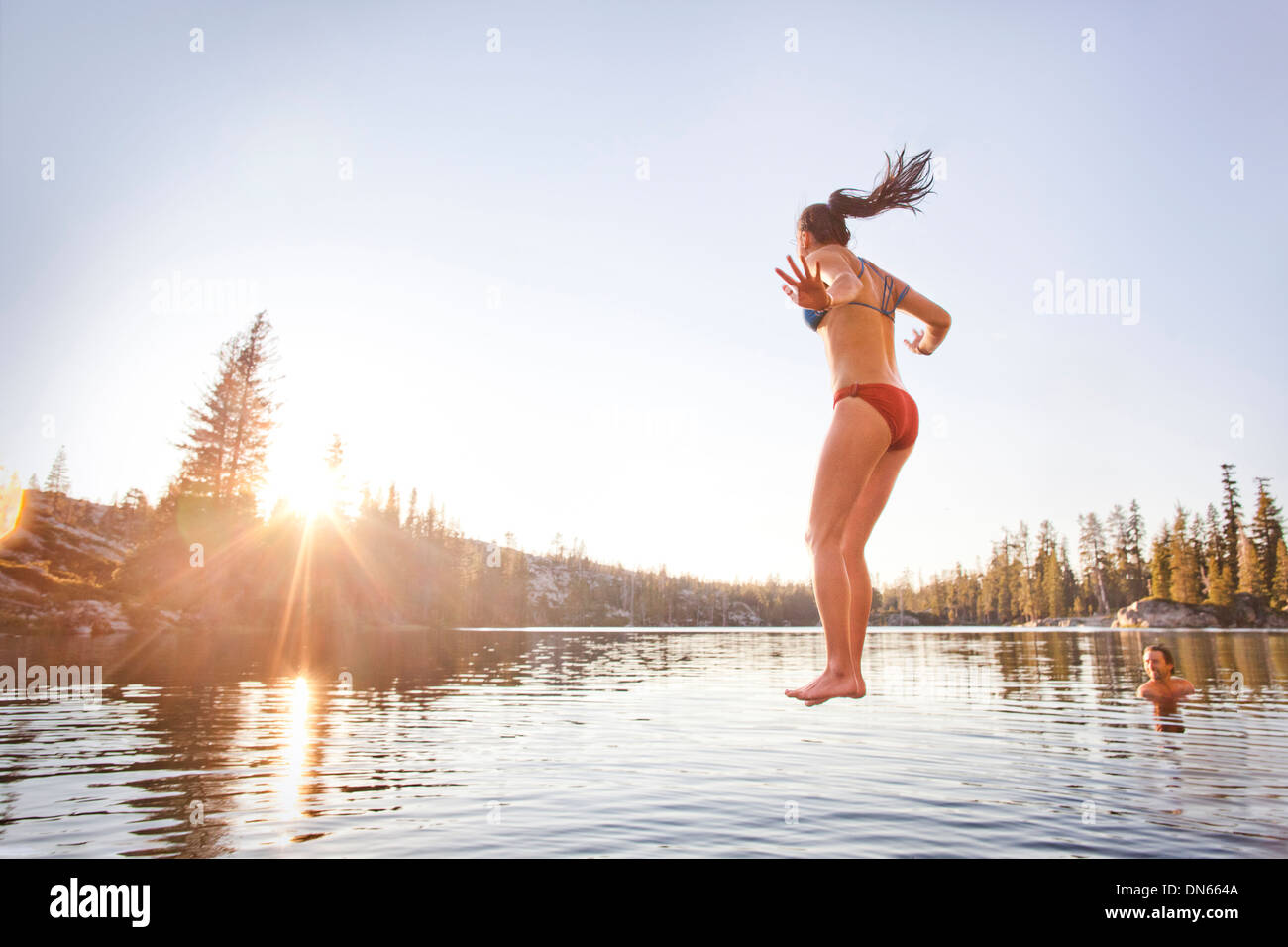 Woman jumping into rural lake Stock Photo