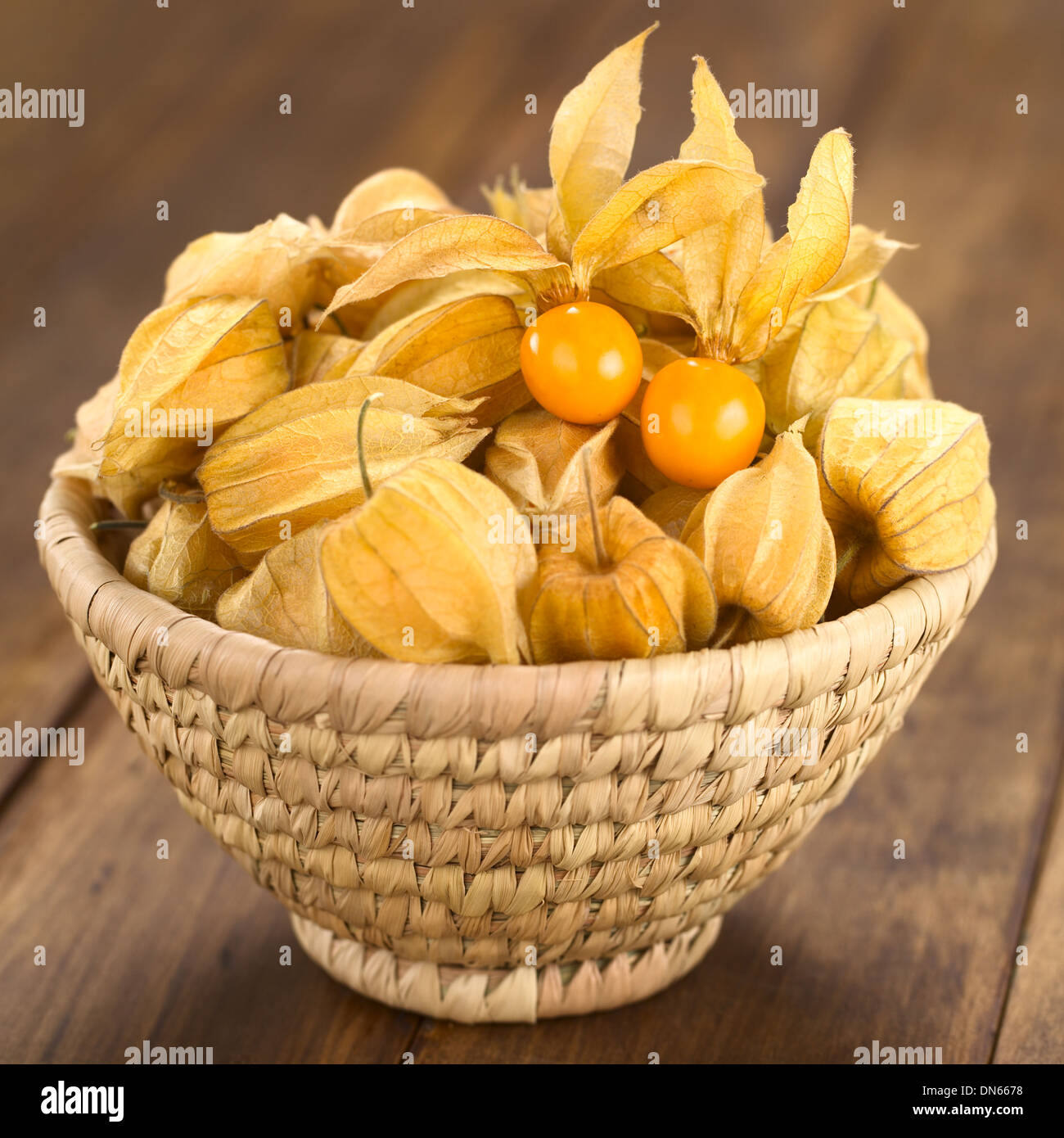 Physalis berry fruits (lat. Physalis peruviana) with husk in basket (Selective Focus, Focus on the open physalis) Stock Photo