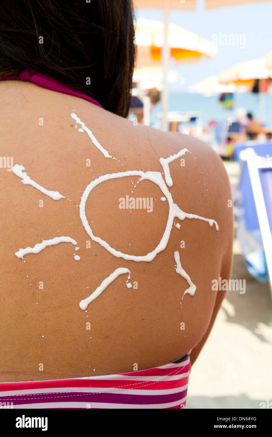 sun cream on woman's shoulder at beach. Stock Photo