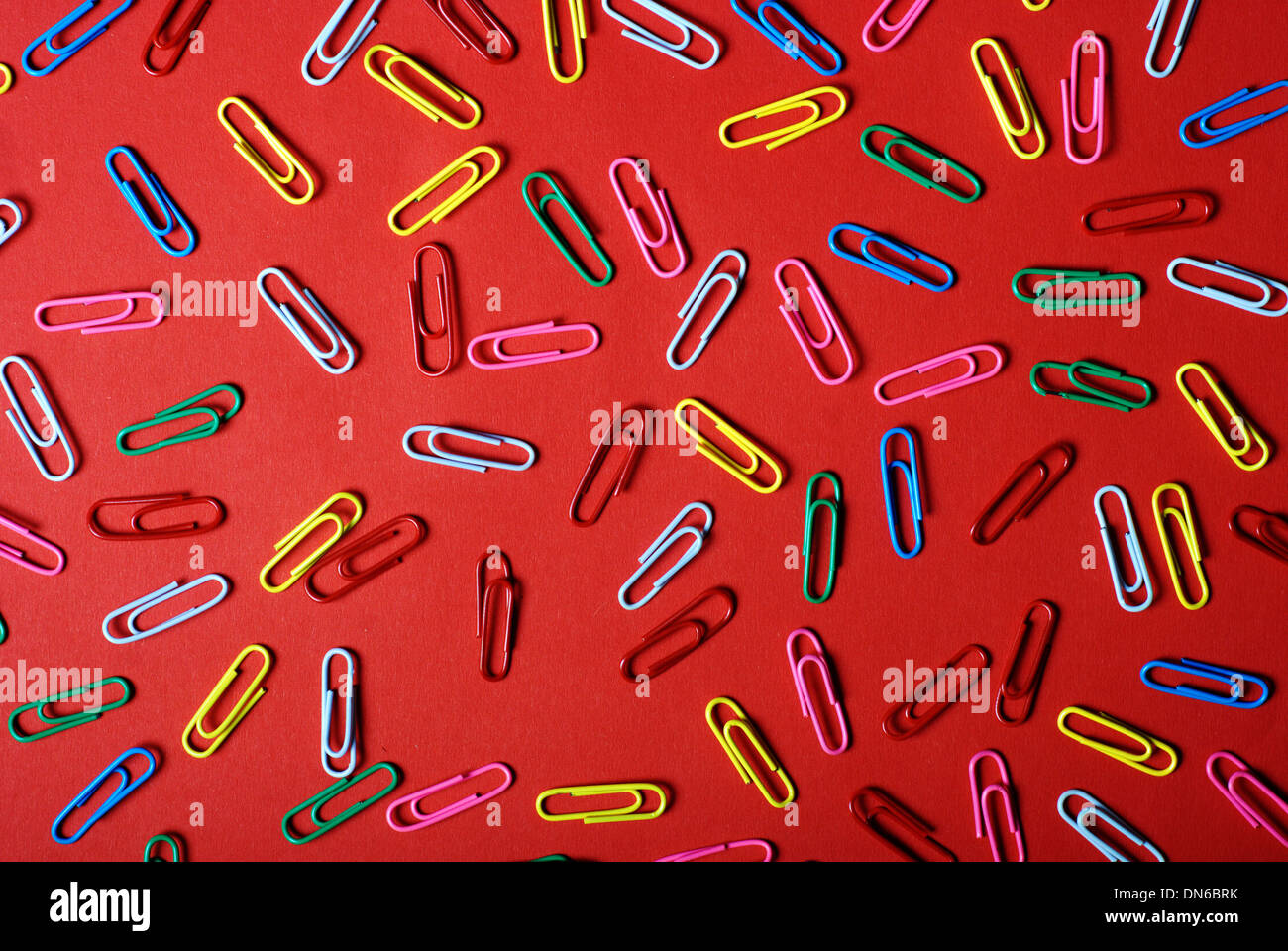colorful paper clip against a red background Stock Photo