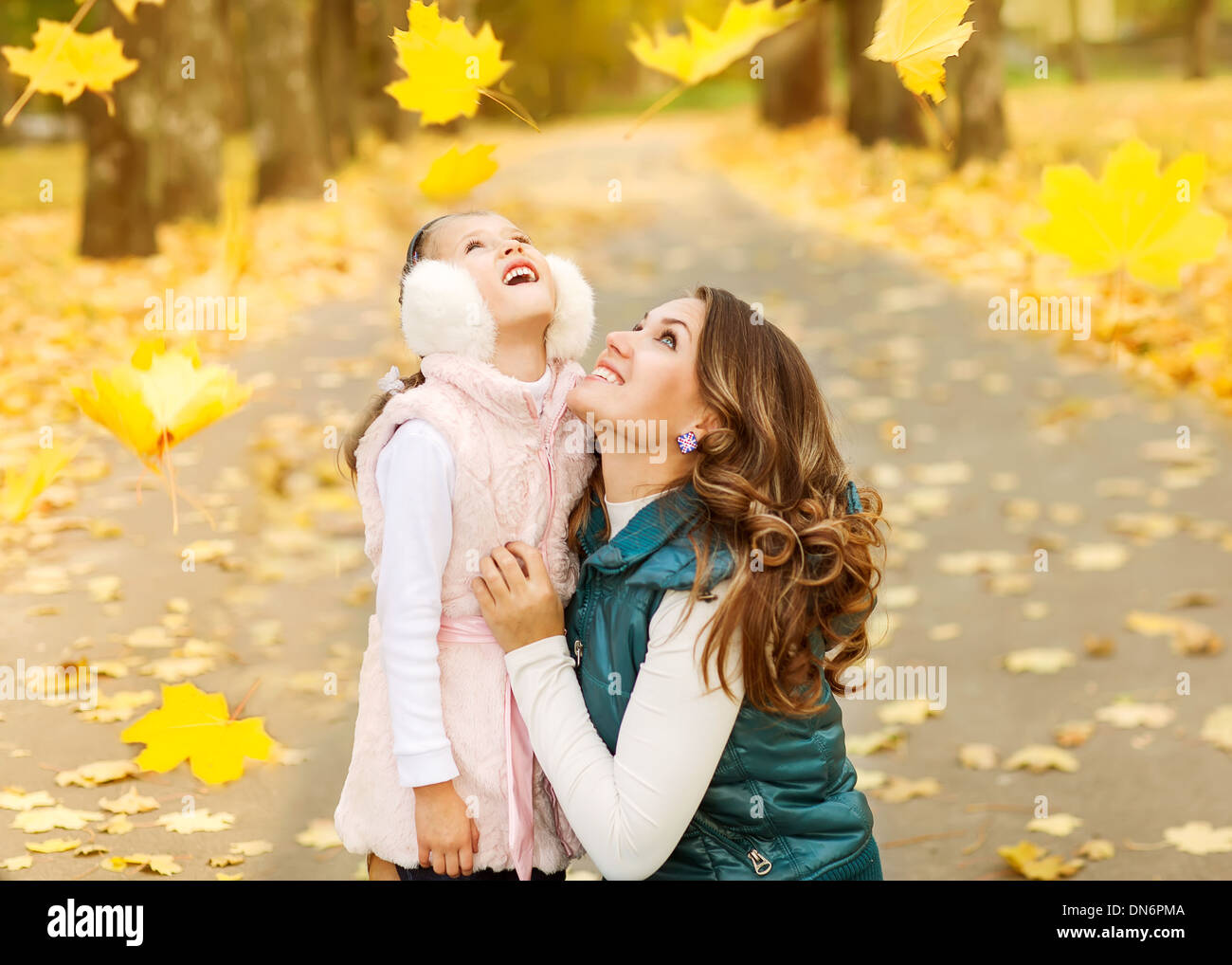 Mother and daughter having fun in the autumn park among the falling ...