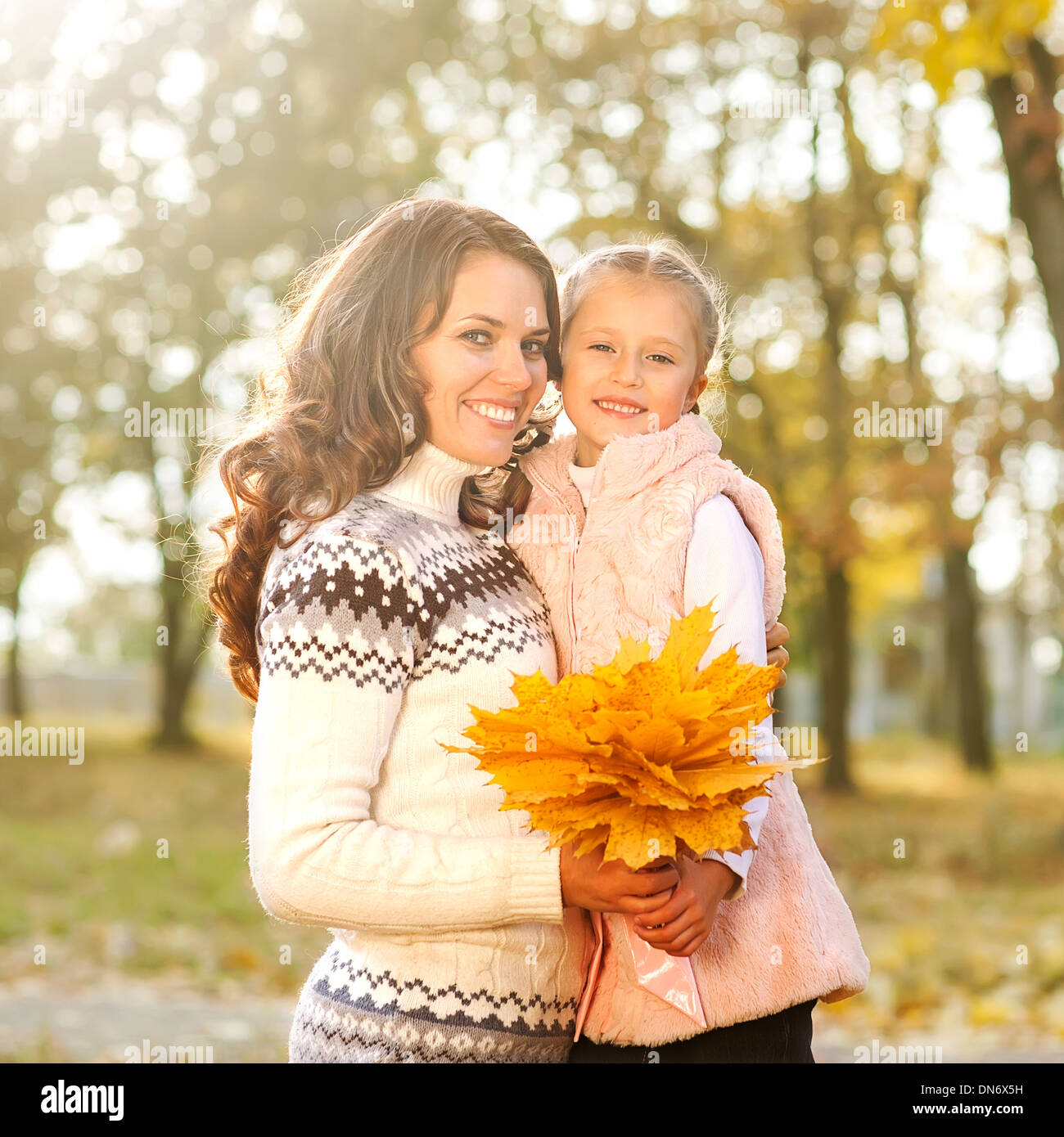 Mother and daughter having fun in the autumn park among the falling ...