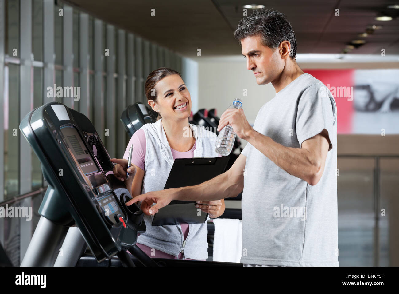 Instructor Looking At Male Client On Treadmill Stock Photo