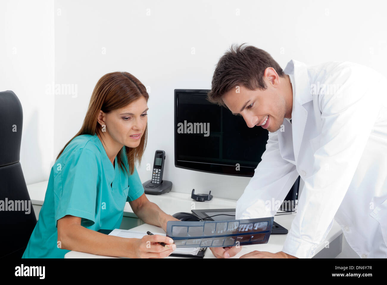 Dentist With Assistant Analyzing X-Ray Report Stock Photo