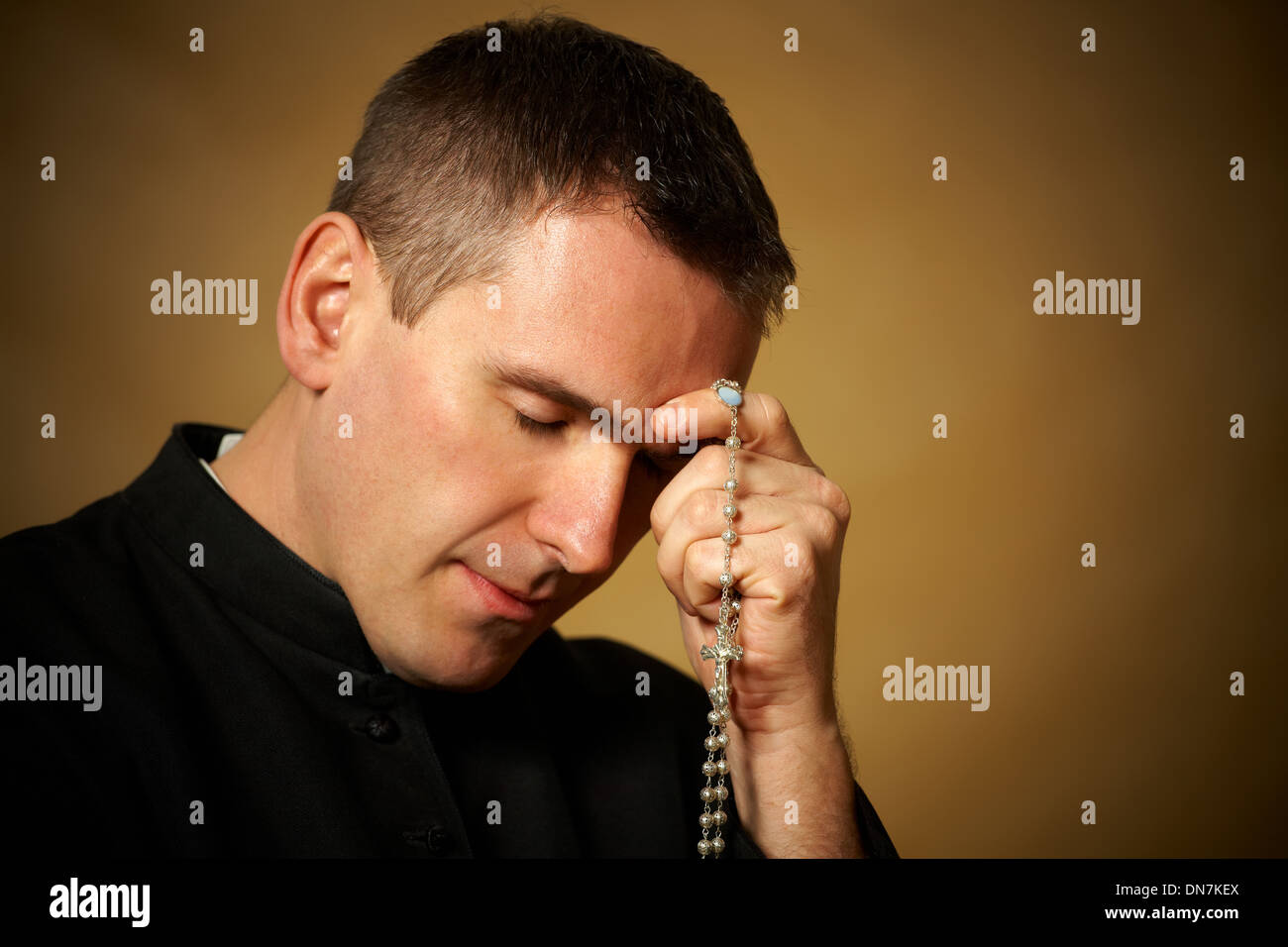 Praying priest with rosary in his hands Stock Photo - Alamy