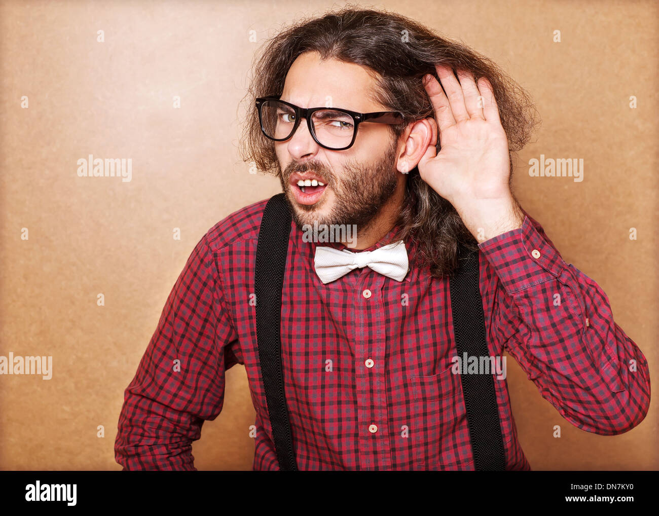 Emotional portrait of a guy who is trying to hear each other, hipster Style, studio shot. Stock Photo