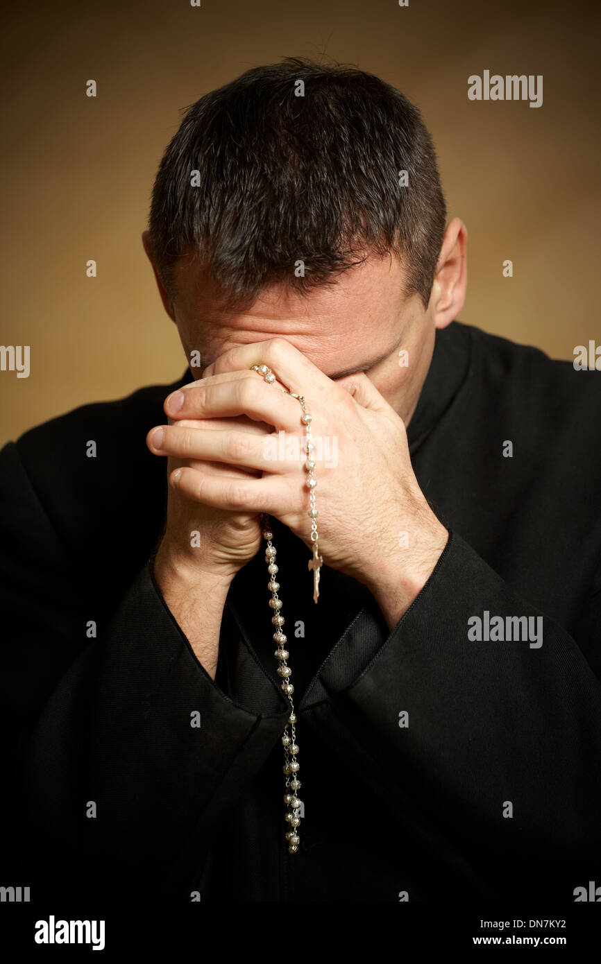 Praying priest with rosary in his hands Stock Photo - Alamy