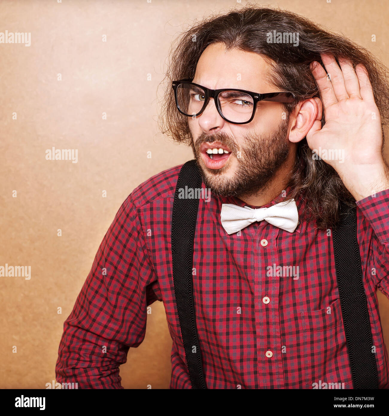 Emotional portrait of a guy who is trying to hear each other, hipster Style, studio shot. Stock Photo