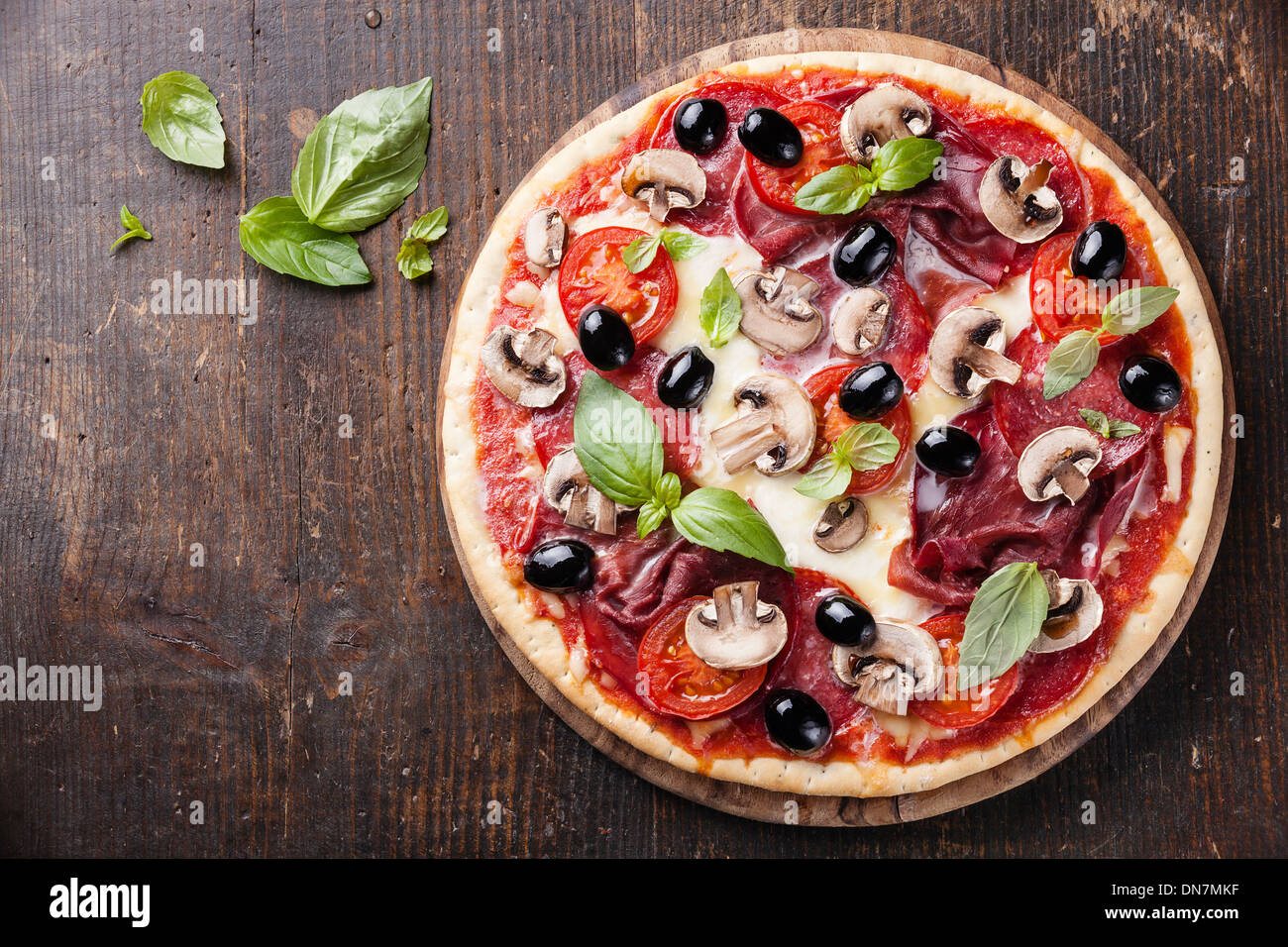 Italian pizza with salami, mushrooms and olives on wooden table Stock Photo