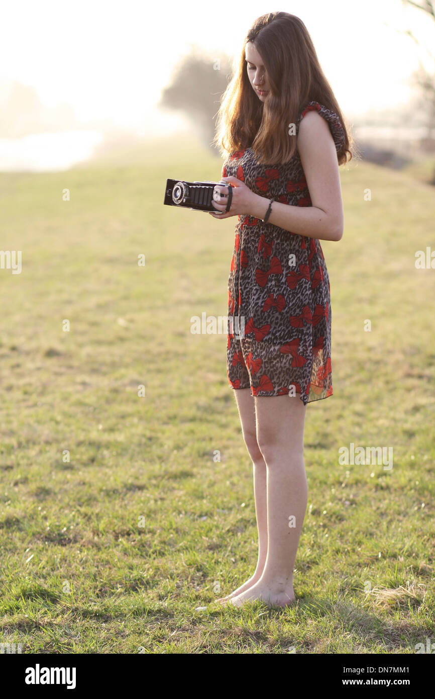 Young woman on a meadow with nostalgic camera Stock Photo