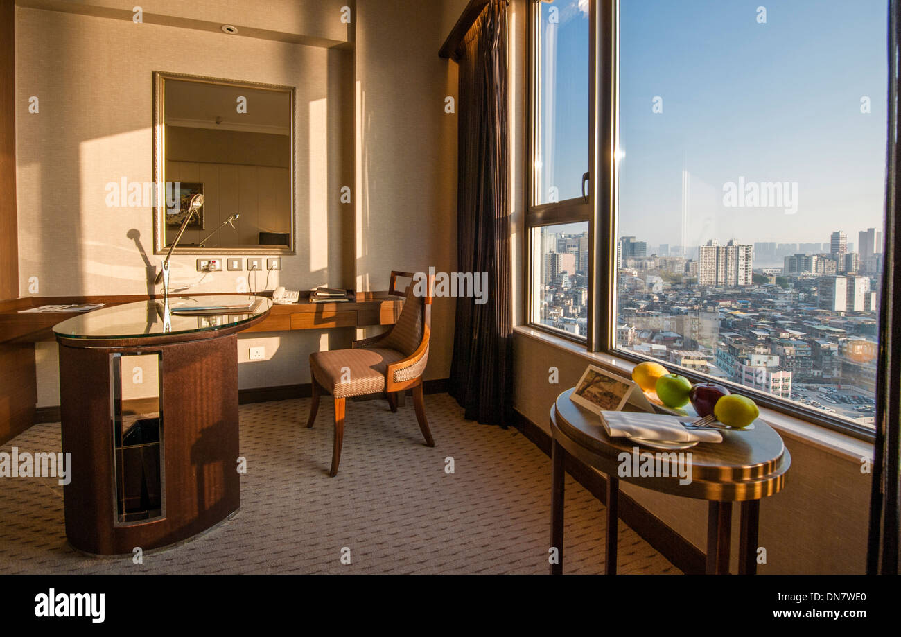 Hotel room 1334 of Sofitel Ponte 16 with desk, chair, lounge table and view of the old town through window, Macau, Macao, China Stock Photo