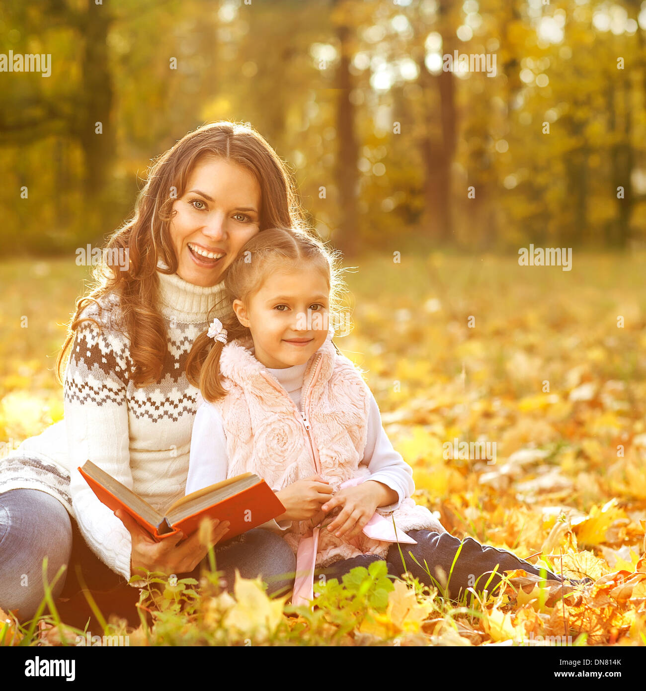 Mother and daughter having fun in the autumn park among the falling ...