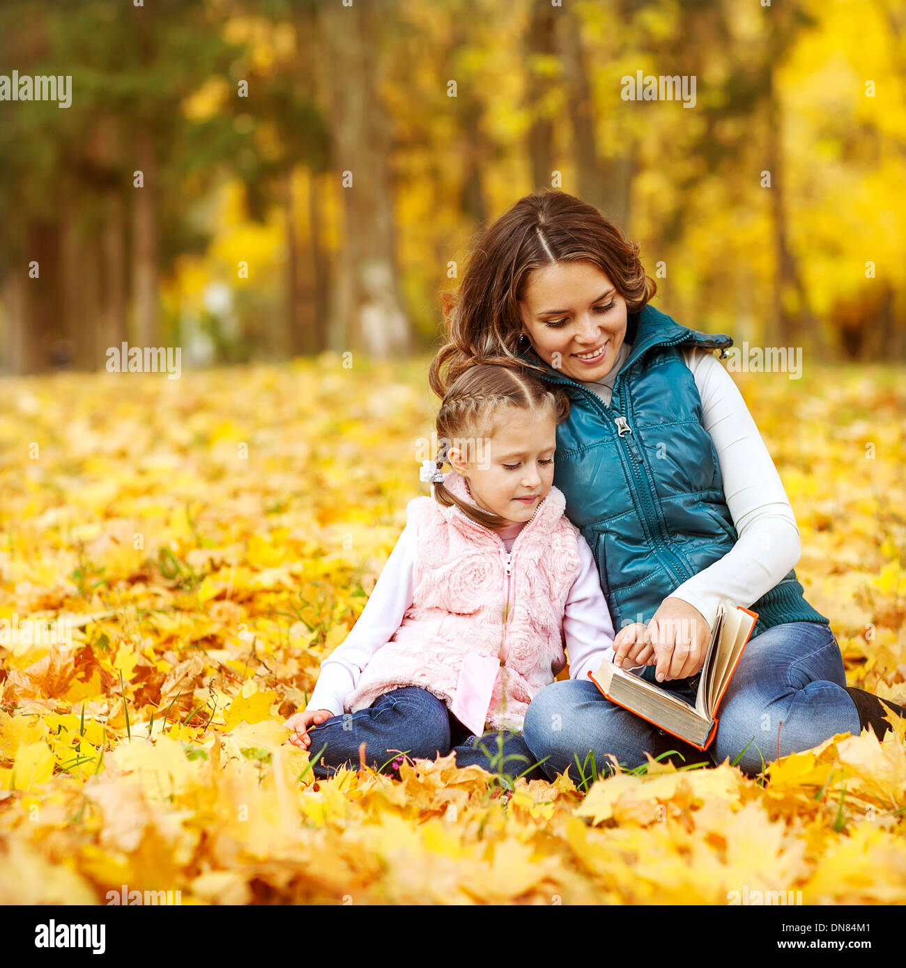 Mother and daughter having fun in the autumn park among the falling ...