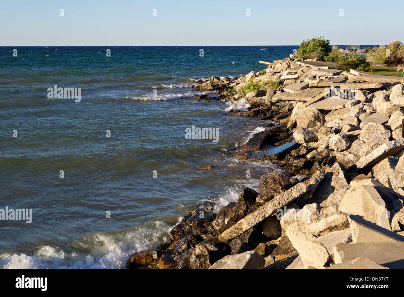 Broken slabs of concrete form a breakwall into Lake Huron at Rogers City Harbor in Michigan Stock Photo