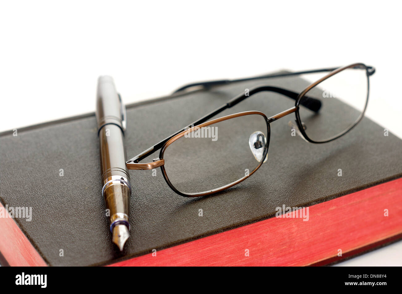 book glasses and feather on bright background Stock Photo