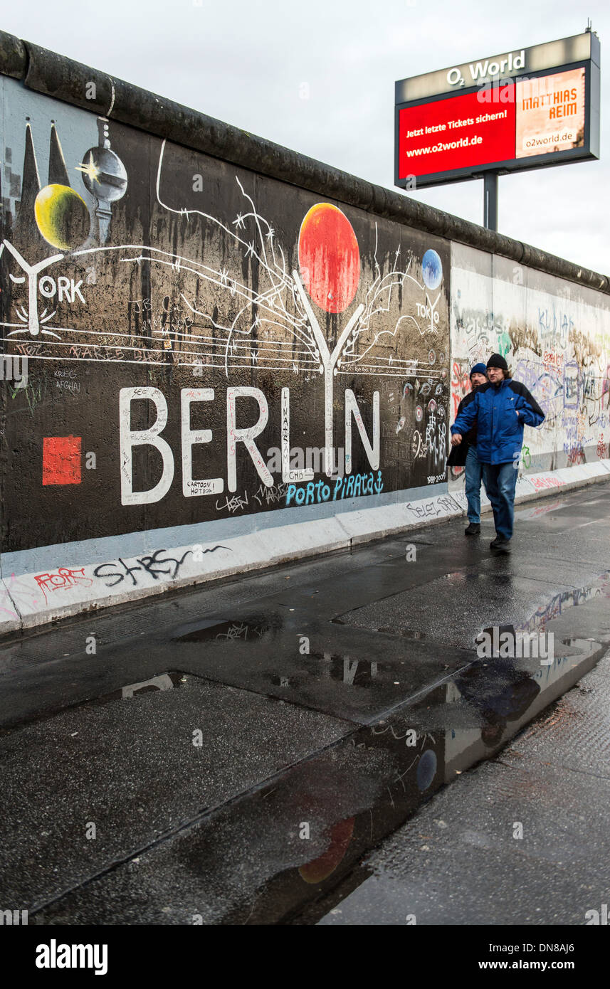 People walking alongside the Berlin wall Germany Europe Stock Photo