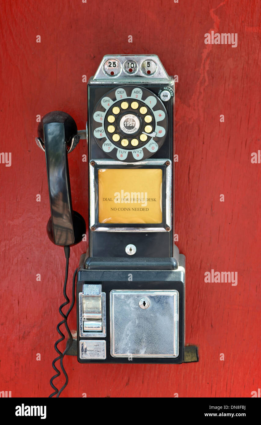 An old fashioned pay phone against a red background Stock Photo
