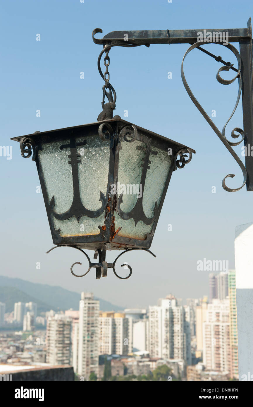 Historic Portuguese lamp of Guia fortress against the skyline of modern high rise buildings, Macau (Macao), SAR of China Stock Photo