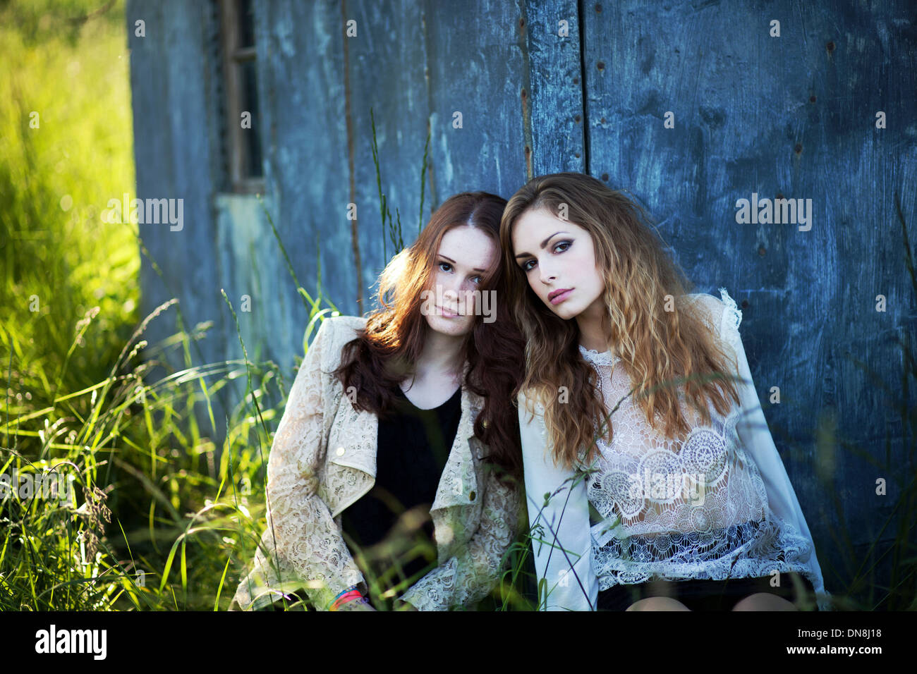 Two women leaning against a house wall Stock Photo