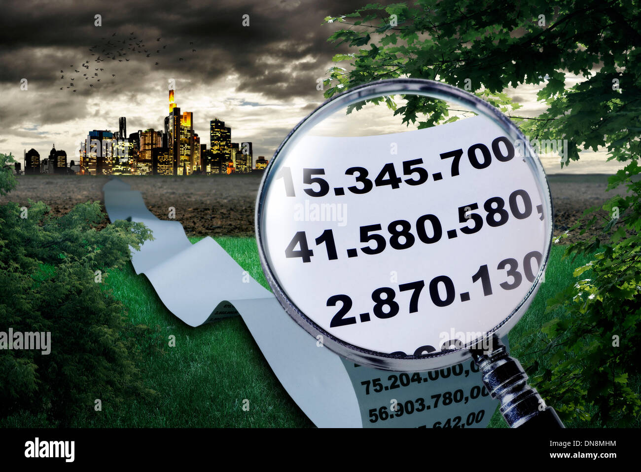 Magnifier shows the enlargement of high sums. In the background a large city can be seen. Stock Photo