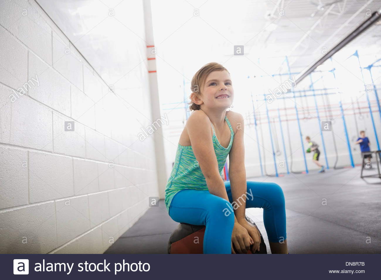 Girl sitting on medicine ball Stock Photo