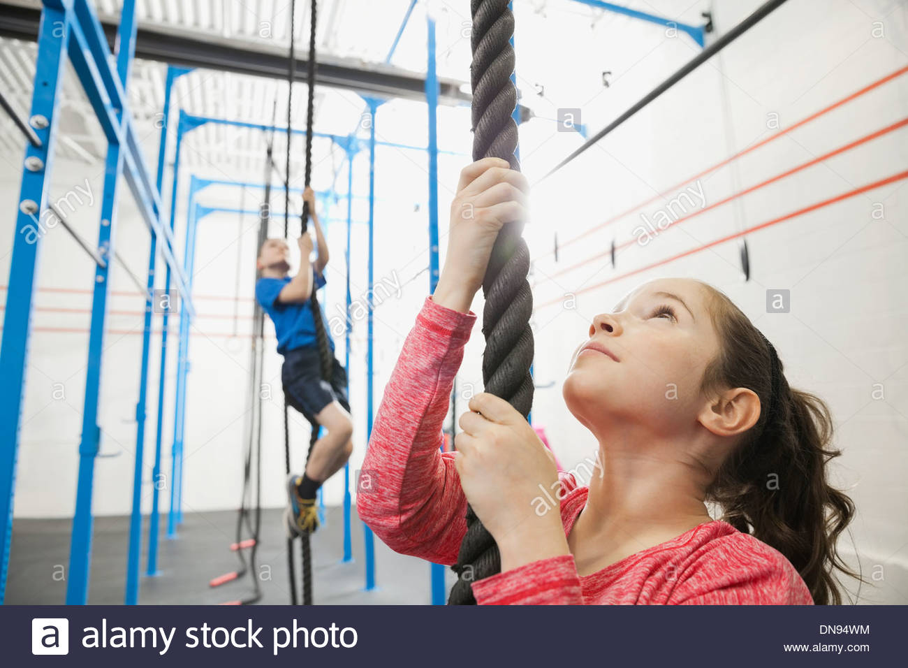 Girl climbing rope in gym Stock Photo
