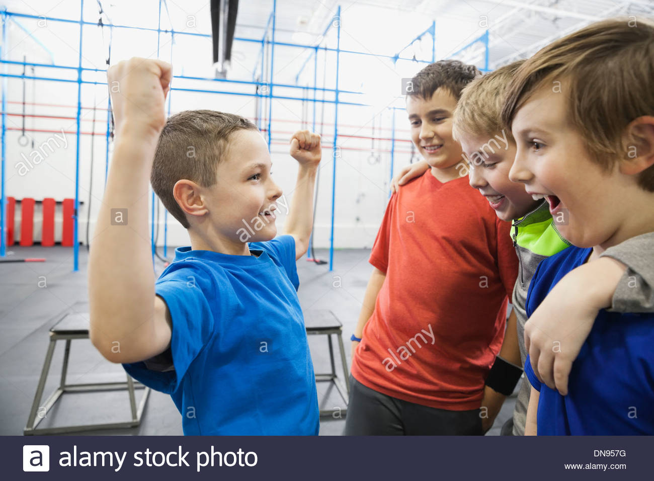 Boy showing muscles to friends in gym Stock Photo
