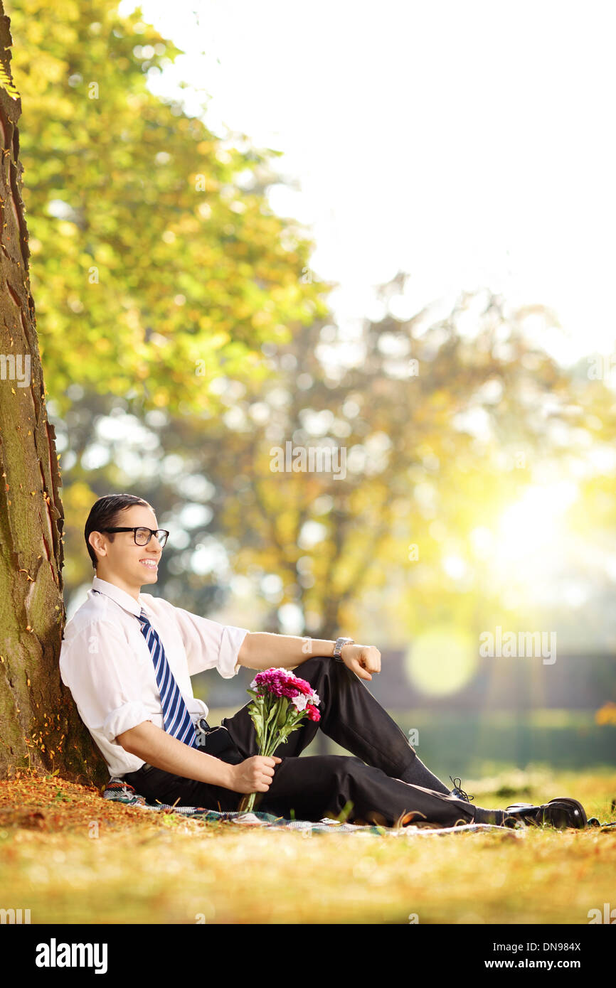 Handsome guy with a bunch of flowers sitting on a grass and relaxing Stock Photo