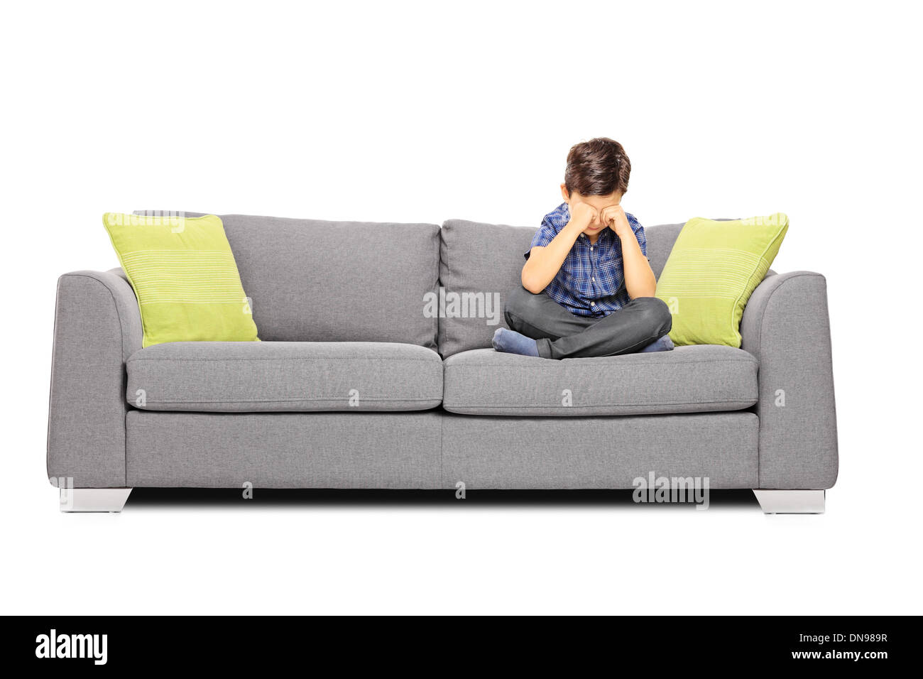 Sad boy sitting on a sofa and crying Stock Photo