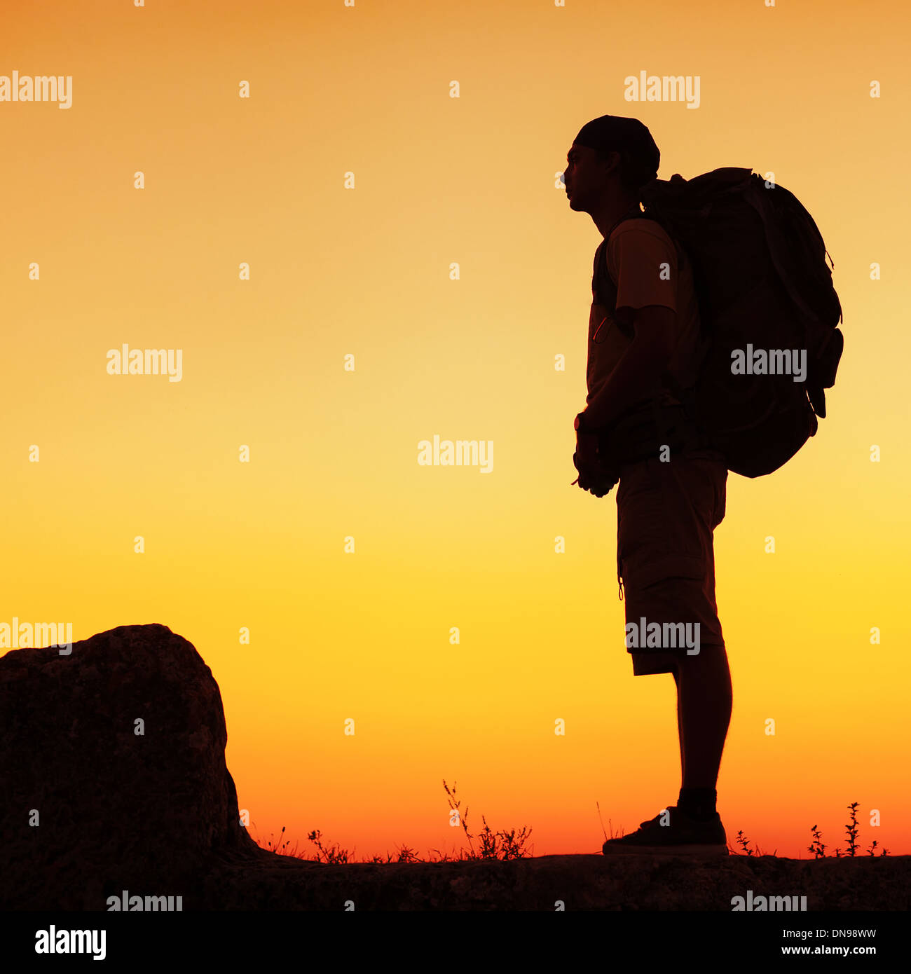 Hiker with backpack standing on top of a mountain and enjoying sunset ...