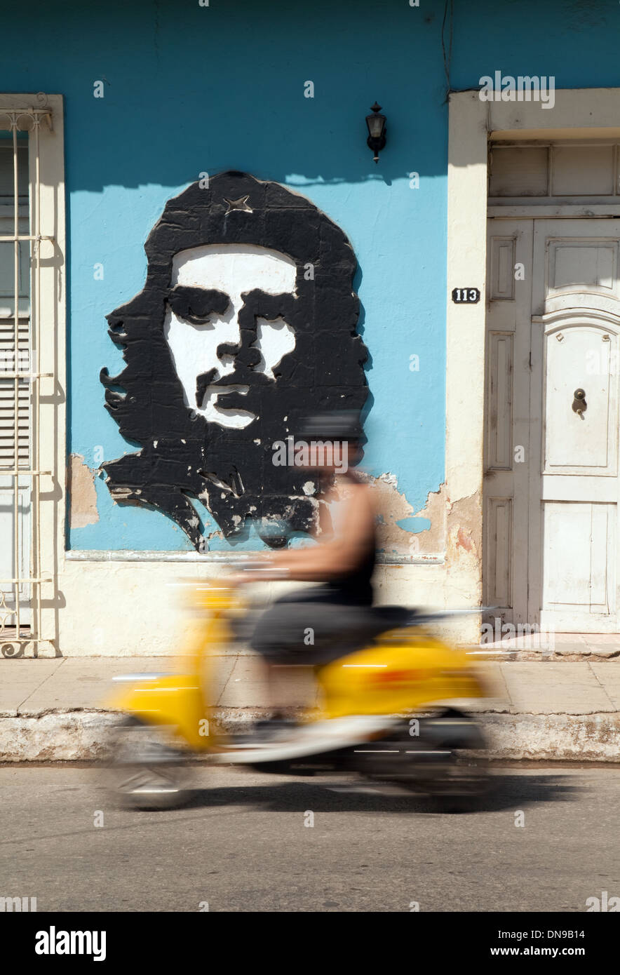 A scooter passes a wall image of Che Guevara, Trinidad, Cuba, Caribbean Stock Photo