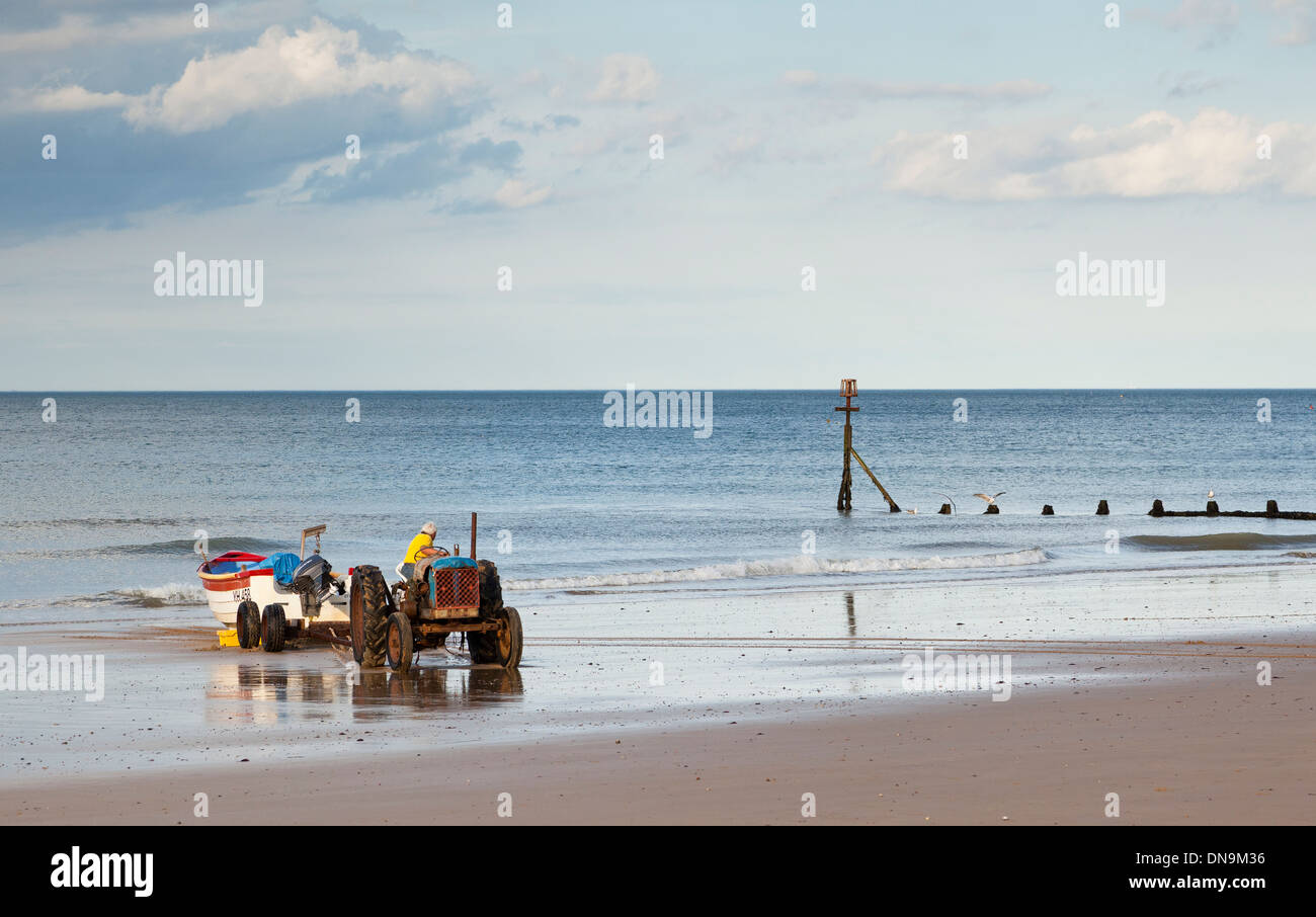 A fisherman driving a Ford tractor, towing his fishing boat out of the sea at Cromer, Norfolk, England UK Stock Photo