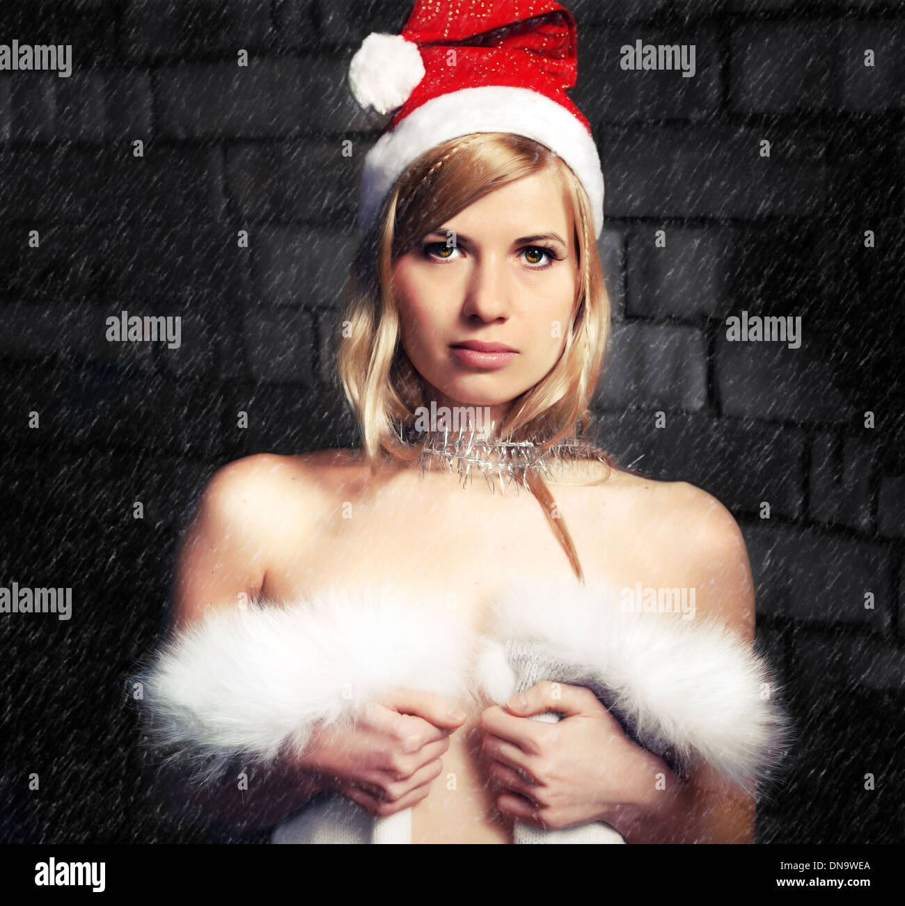 Young blond woman in a Santa Claus hat on a background of falling snow Stock Photo