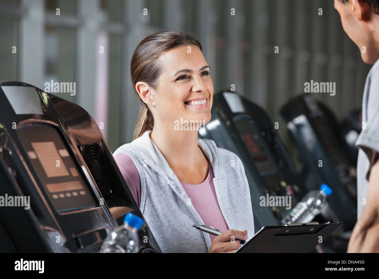 Instructor Looking At Male Client Exercising On Treadmill Stock Photo