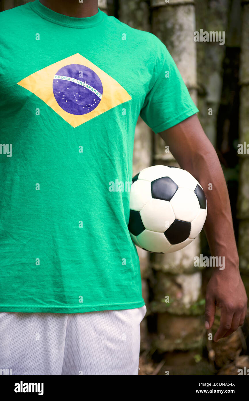 brazilian-soccer-player-stands-with-football-in-front-of-tropical