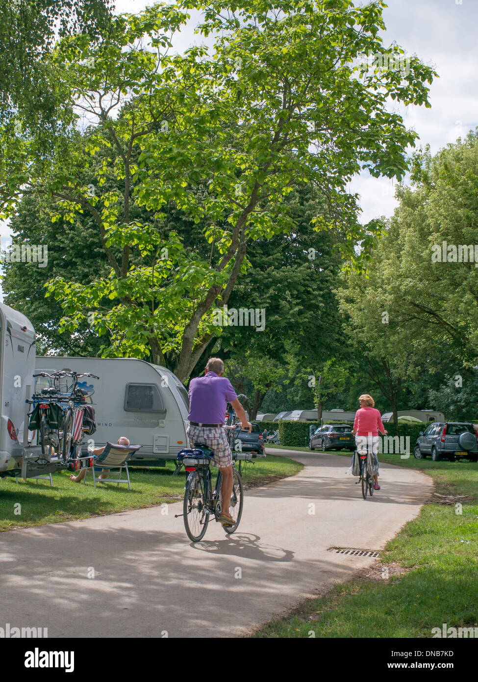 Couple cycling through  a caravan park or campsite in Chagny Burgundy  France Stock Photo