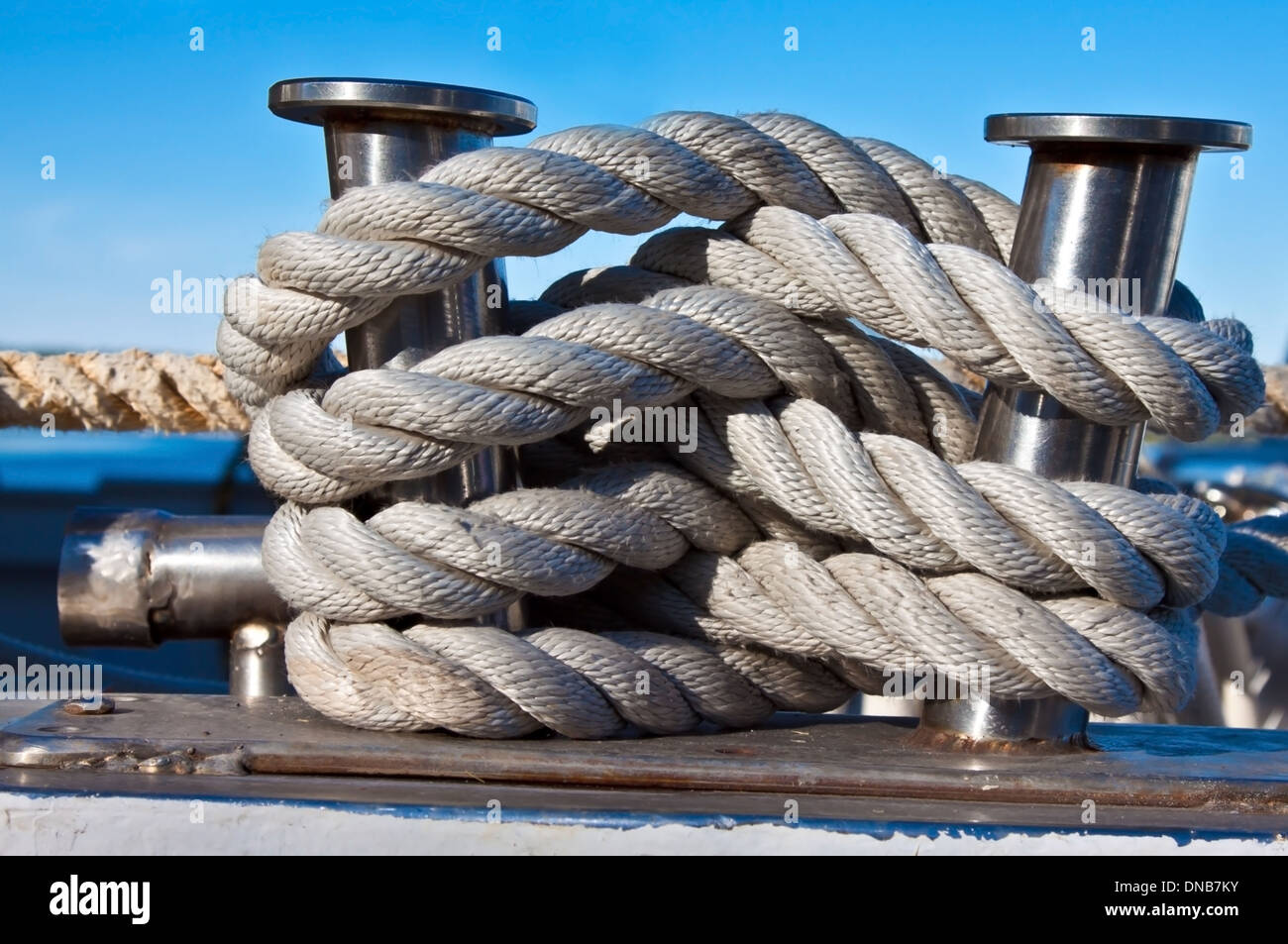 Bundle of rope on the silver mooring bollard on deck Stock Photo