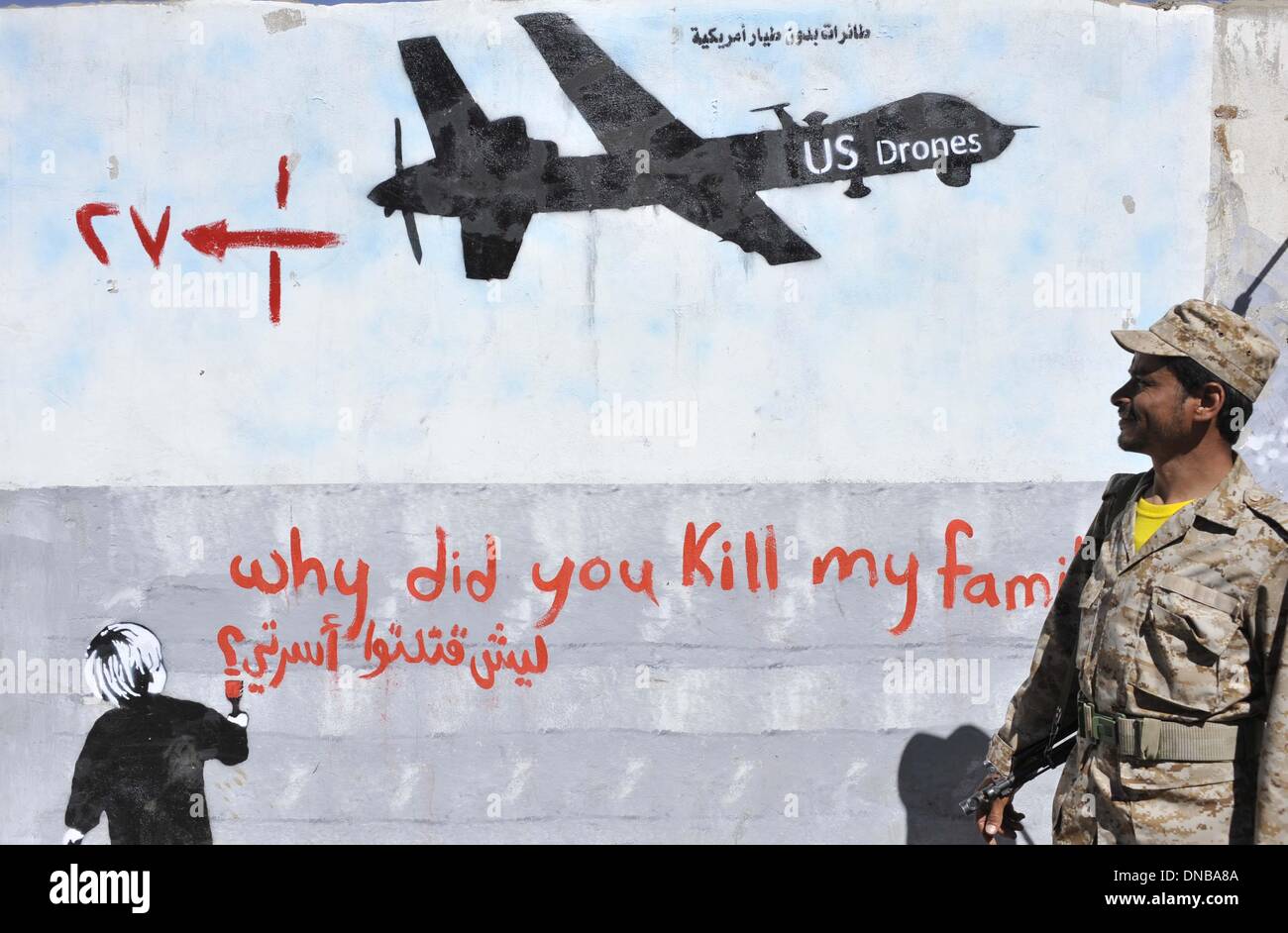 Sanaa, Yemen. 21st Dec 2013. A Yemeni soldier looks at the graffiti of U.S. drone strike painted on a wall as a protest against the drone strikes, in Sanaa, Yemen, on Dec. 21, 2013. The Yemeni parliament on Sunday approved a ban on U.S. drones in the country after dozens of civilians were killed by the unmanned aircraft, the official Saba news agency reported. The decision was made after the U.S. drone mistakenly hit a wedding convey on Thursday in Yemen's southeastern province of al- Bayda, killing up to 17 Yemeni civilians and wounding about 21 others. Credit: Xinhua/Alamy Live News Stock Photo