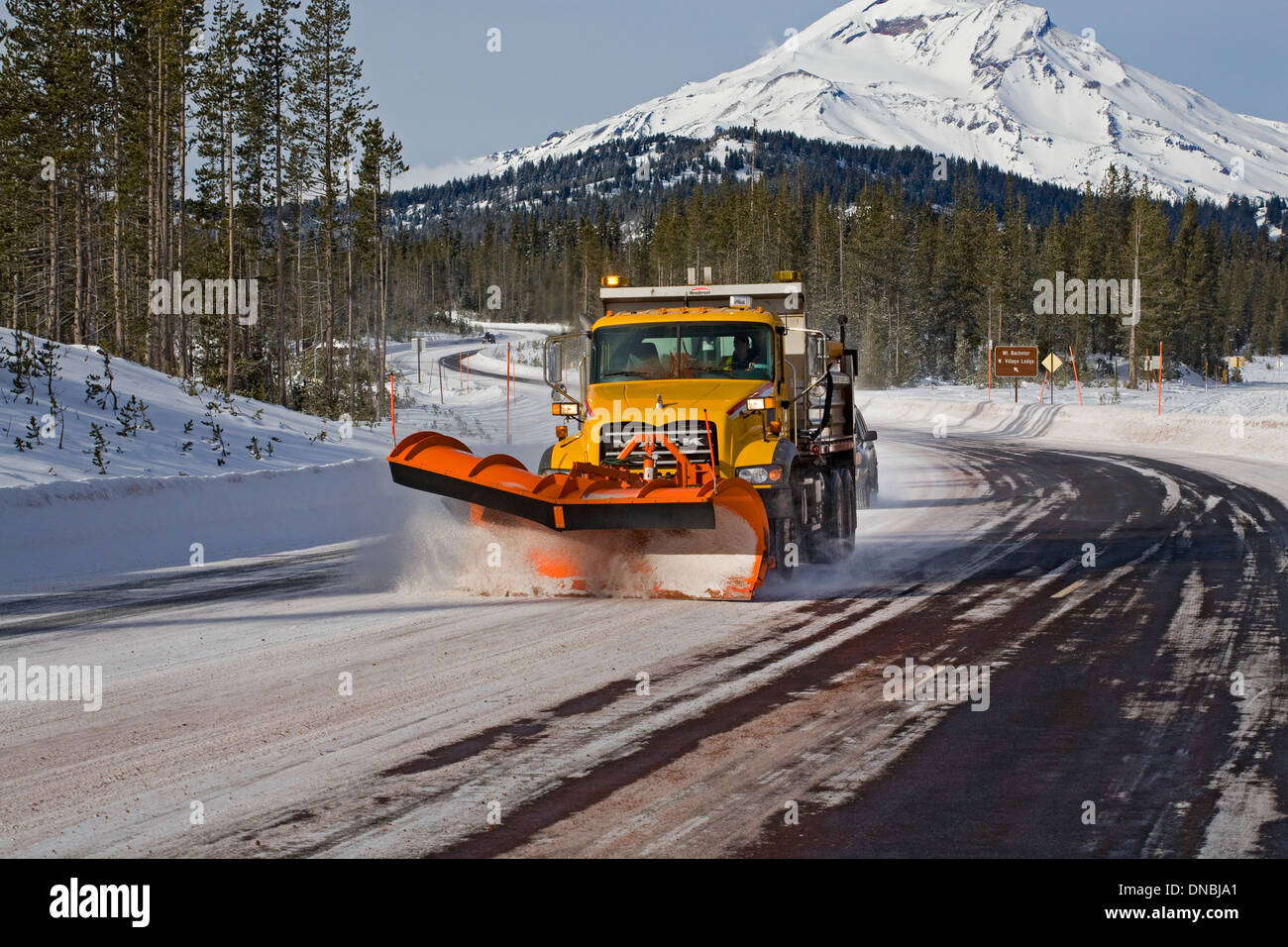A snow plow and sanding truck clears a mountain highway of snow