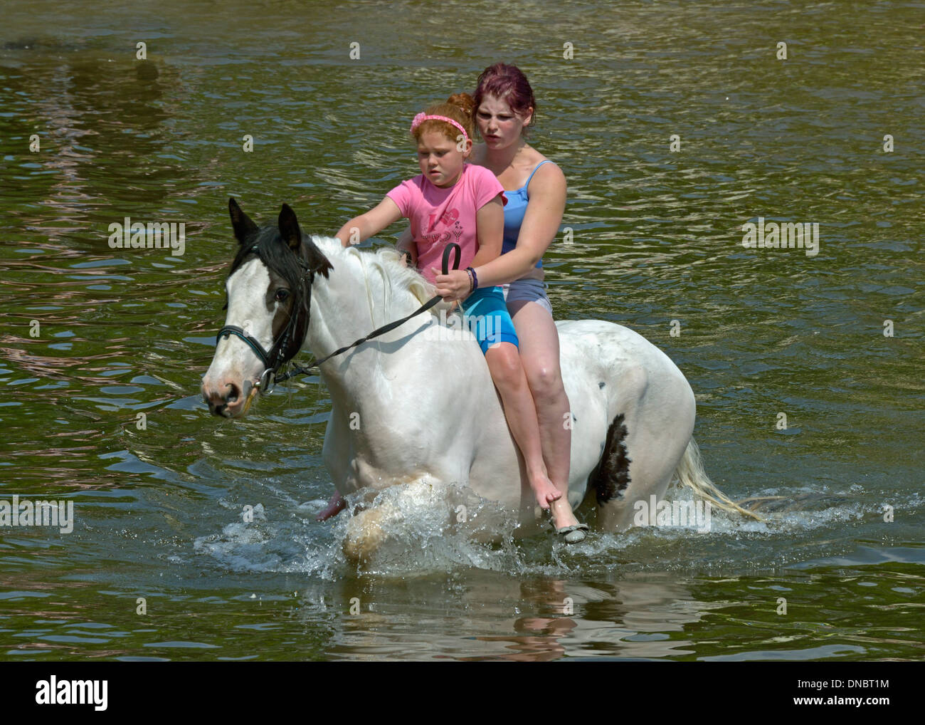 Gypsy traveller girls riding horse in River Eden. Appleby Horse Fair, June 2013. Appleby-in-Westmorland, Cumbria, England. Stock Photo