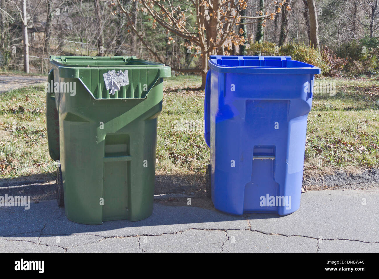 A green trash bin next to a blue recycle bin sit emptied out on the
