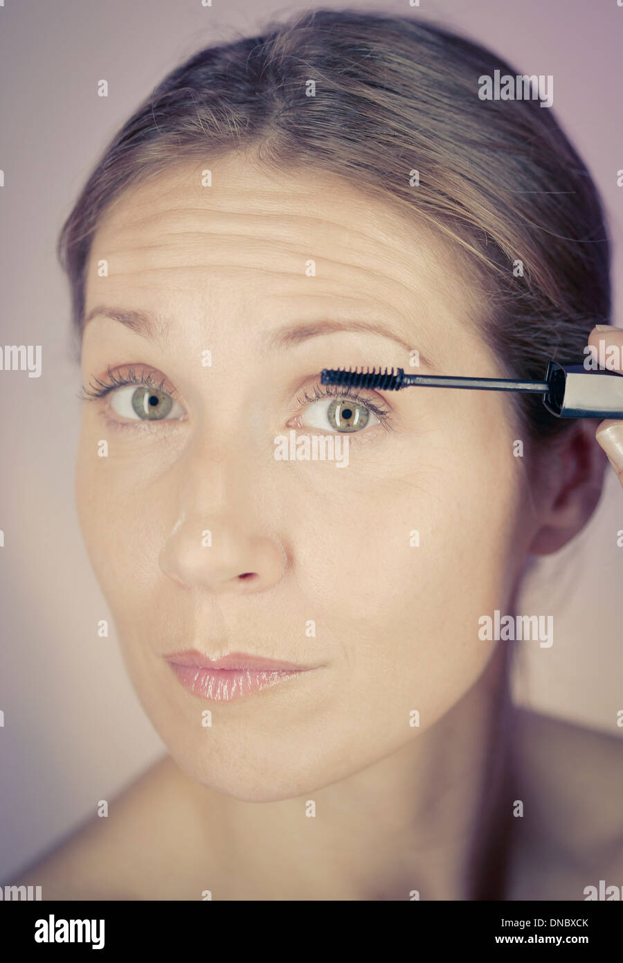 A middle aged woman applying mascara Stock Photo
