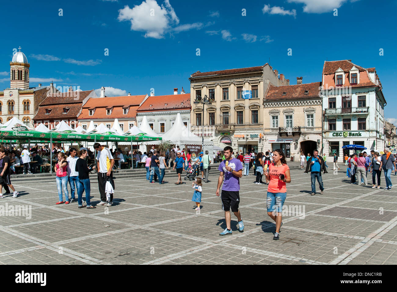 Pedestrians in Brașov Council Square (Piața Sfatului) in the old town in Brasov, a city in the Transylvania region of Romania. Stock Photo